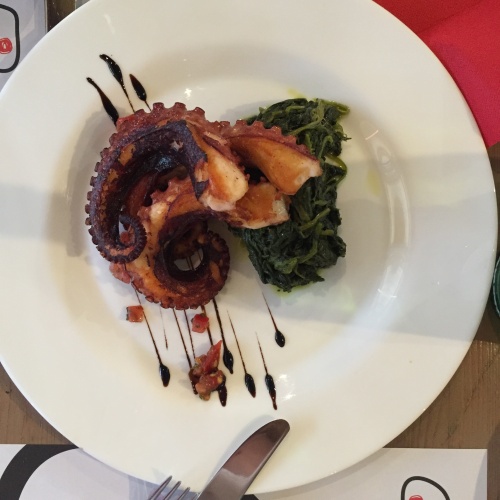 Perfectly roasted octopus on a bed of sauteed greens.